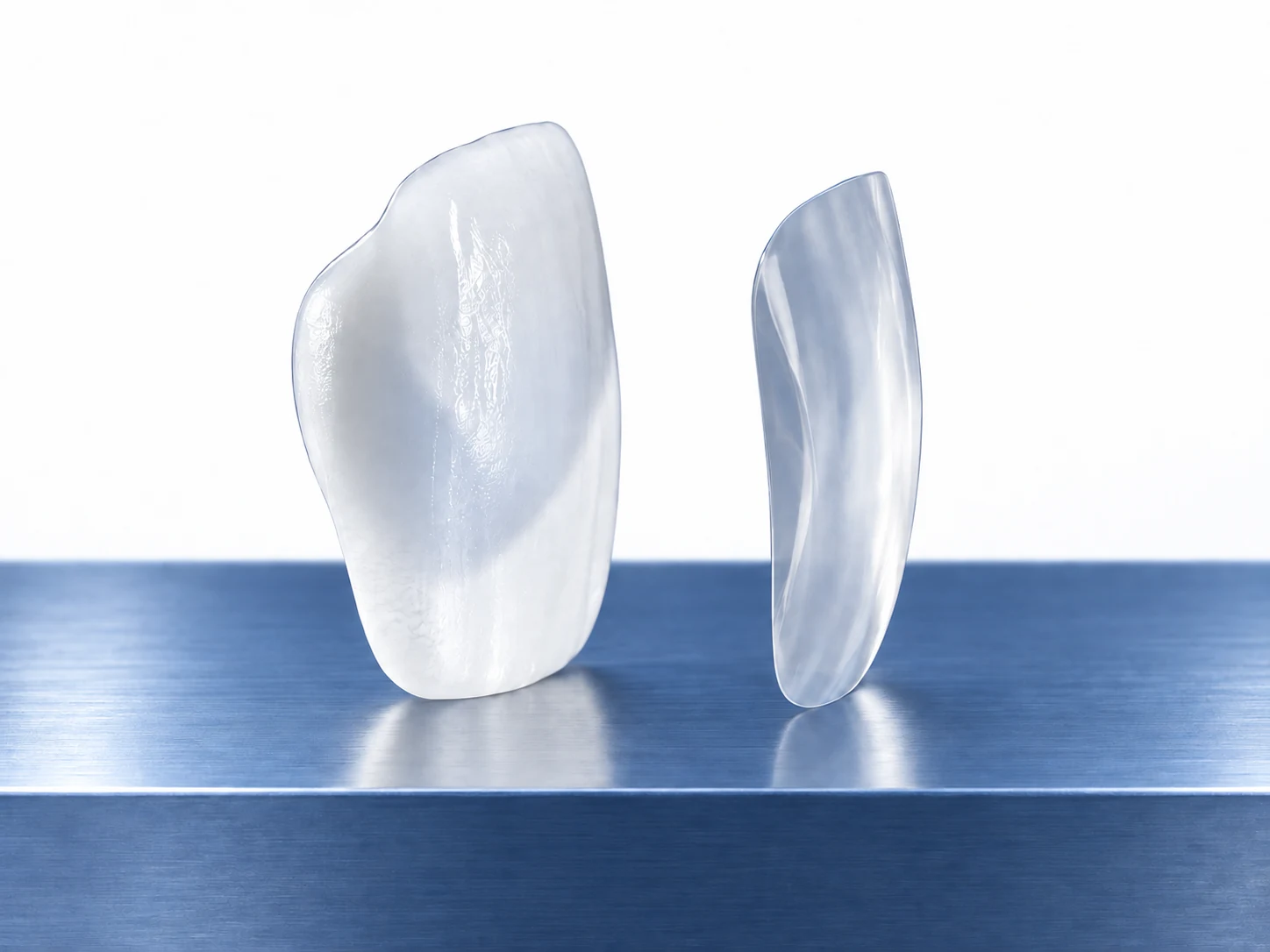 Two ceramic veneers with different illustrative profiles on a blue steel shelf